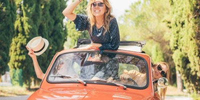 Three girls best friends enjoying summer trip in Tuscany with red vintage car